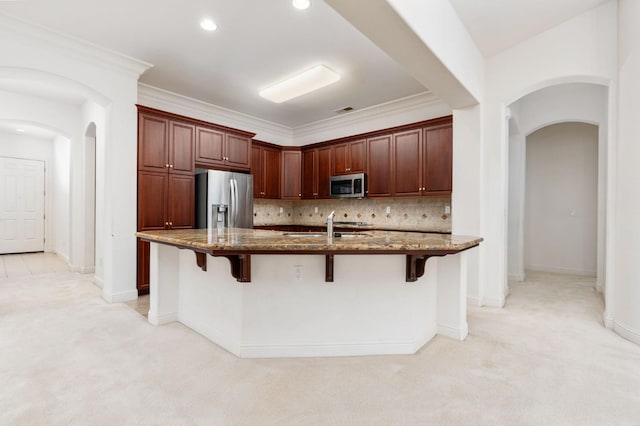 kitchen featuring light carpet, tasteful backsplash, arched walkways, and stainless steel appliances