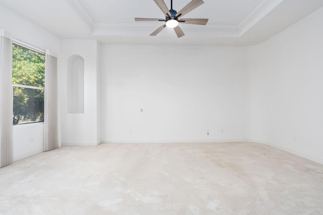 empty room with light carpet, baseboards, a raised ceiling, and crown molding