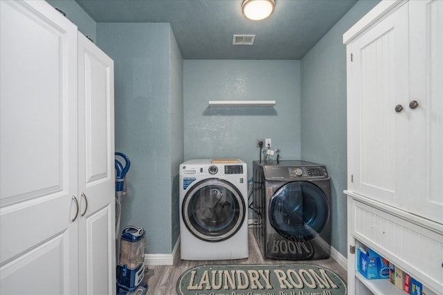 29598 Jim Bowie Ct, Coarsegold, CA 93614 - clothes washing area with wood finished floors, visible vents, baseboards, cabinet space, and washer and clothes dryer