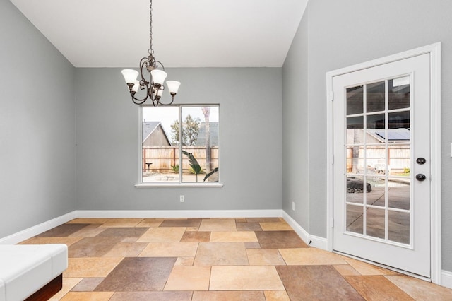 unfurnished dining area with stone finish floor, an inviting chandelier, and baseboards