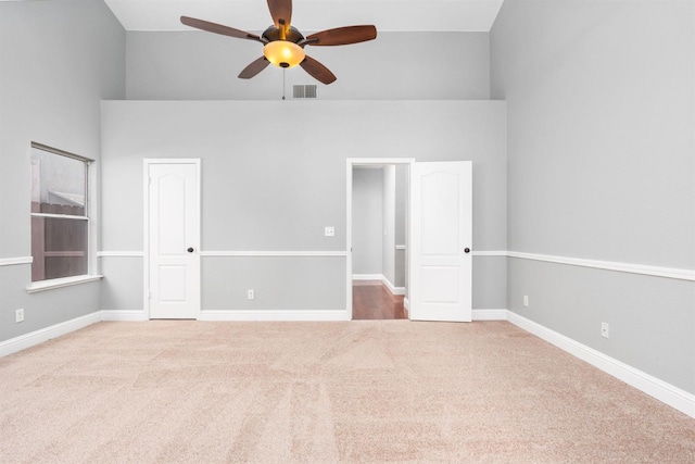 unfurnished room featuring carpet floors, visible vents, ceiling fan, and baseboards