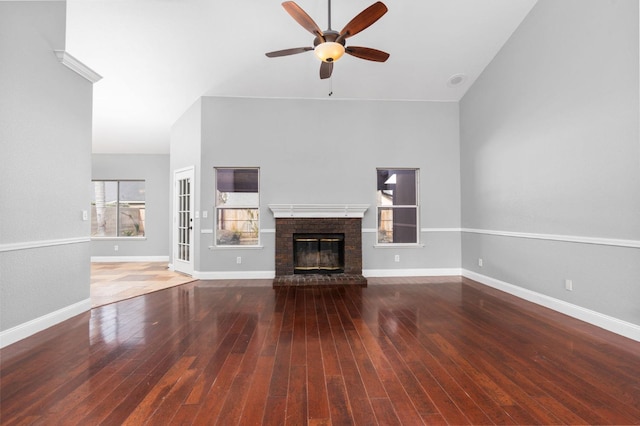 unfurnished living room featuring a ceiling fan, a brick fireplace, wood-type flooring, and baseboards