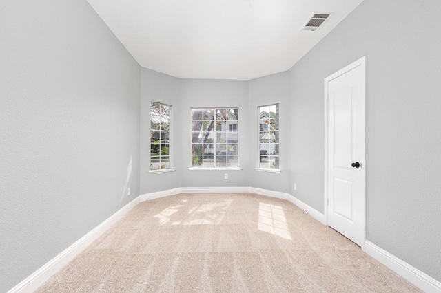 unfurnished room with carpet, visible vents, and baseboards