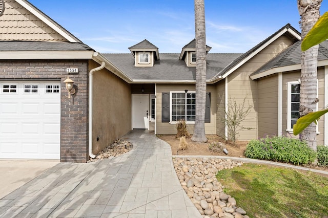 view of front of house featuring roof with shingles, brick siding, and an attached garage