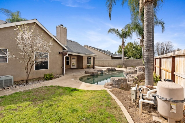 back of property with a fenced in pool, a yard, a chimney, stucco siding, and a fenced backyard