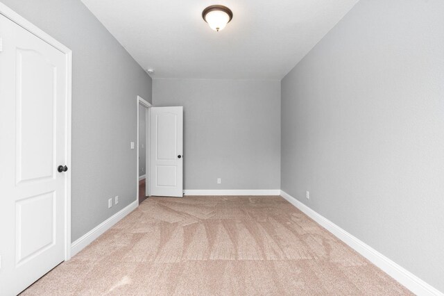 carpeted empty room featuring baseboards