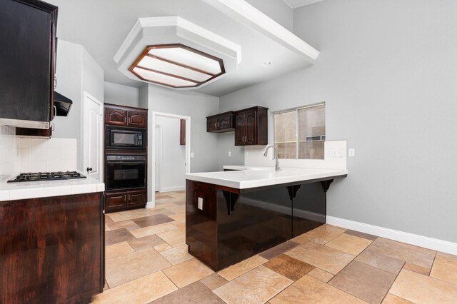 kitchen with dark brown cabinetry, baseboards, a peninsula, extractor fan, and black appliances