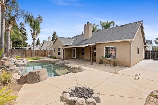 rear view of house featuring a shingled roof, a patio, a fenced backyard, a chimney, and stucco siding