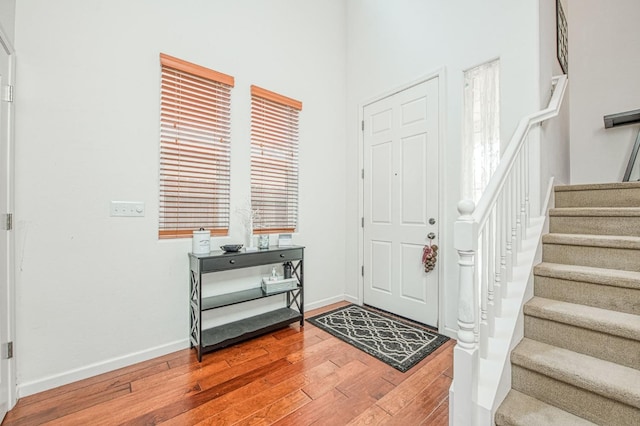 foyer with hardwood / wood-style floors, stairway, and baseboards