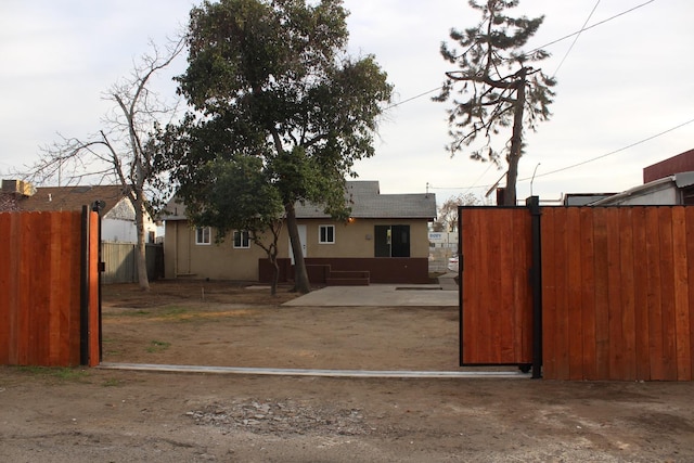 view of front of home with stucco siding, a patio, and fence