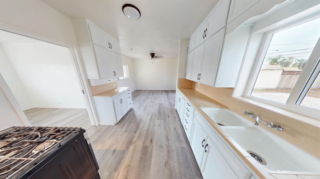 kitchen featuring a healthy amount of sunlight, white cabinets, and gas range oven