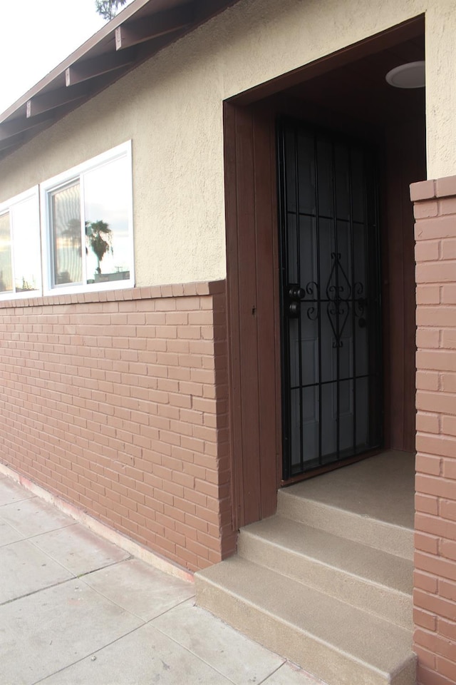 entrance to property featuring brick siding and stucco siding