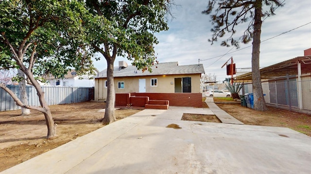 back of house with stucco siding, brick siding, a patio area, and fence