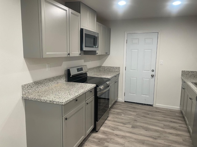 kitchen featuring appliances with stainless steel finishes, light wood-style floors, and gray cabinetry