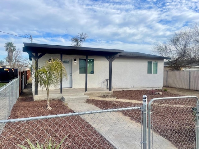 view of front of property with a fenced front yard, a gate, a porch, and stucco siding