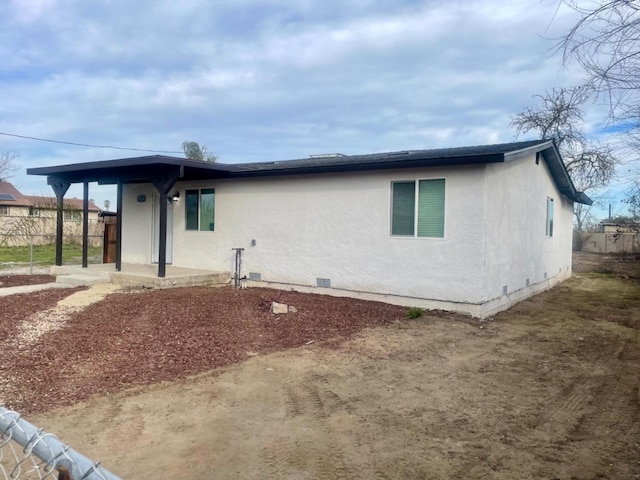 exterior space featuring a patio, crawl space, fence, and stucco siding