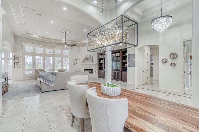 dining area featuring arched walkways, a fireplace, a high ceiling, and ceiling fan with notable chandelier