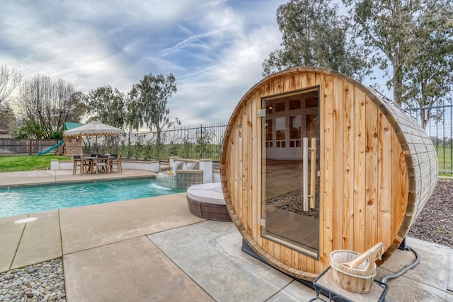 view of swimming pool with a fenced backyard, an outbuilding, a fenced in pool, and a patio