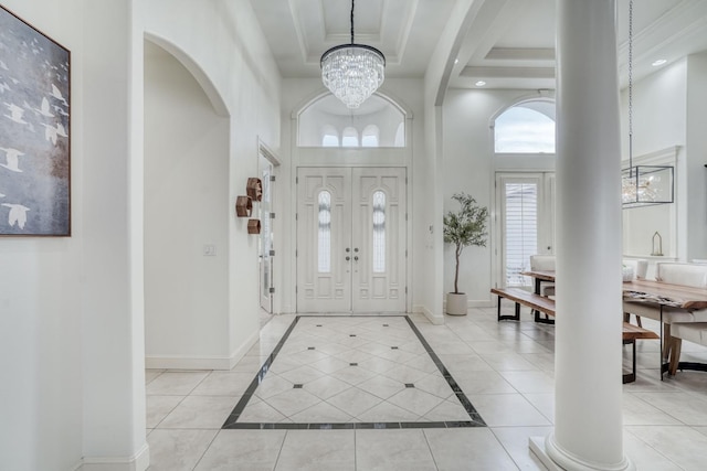 entrance foyer featuring a towering ceiling, baseboards, a raised ceiling, and a notable chandelier