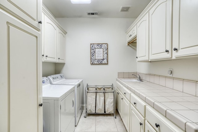 laundry area with a sink, visible vents, washing machine and clothes dryer, and cabinet space