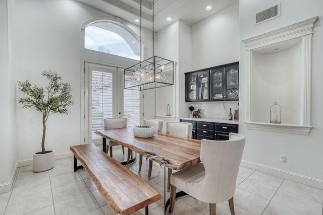 dining room featuring french doors, visible vents, a towering ceiling, light tile patterned flooring, and baseboards