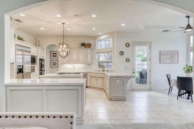 kitchen with arched walkways, a peninsula, and built in appliances