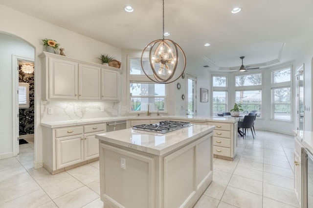 kitchen featuring light tile patterned floors, a peninsula, a kitchen island, appliances with stainless steel finishes, and a tray ceiling