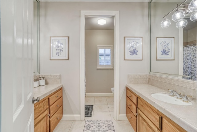 full bathroom featuring toilet, decorative backsplash, vanity, baseboards, and tile patterned floors