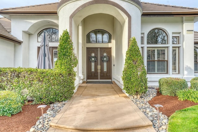 entrance to property with a tiled roof and stucco siding