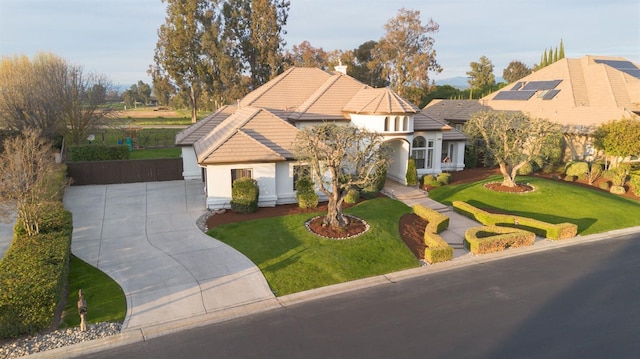 view of front of property featuring driveway, stucco siding, a tile roof, and a front yard