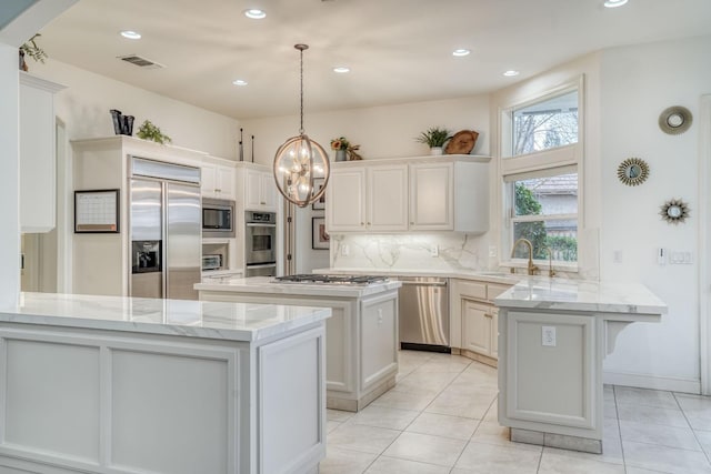 kitchen with visible vents, backsplash, a sink, built in appliances, and a peninsula