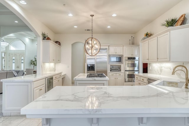 kitchen featuring decorative backsplash, wine cooler, a kitchen island, built in appliances, and a peninsula