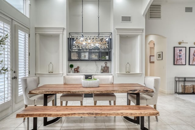 dining room with arched walkways, a high ceiling, light tile patterned flooring, and visible vents