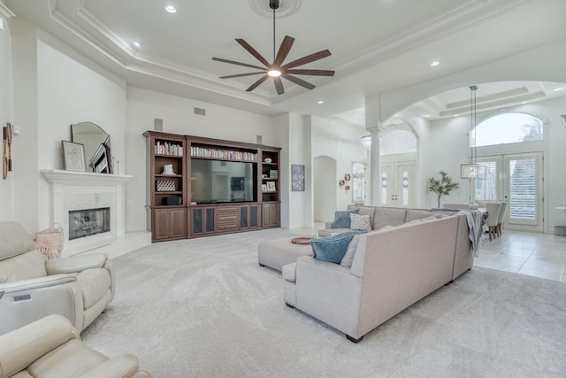 living room with arched walkways, a tray ceiling, carpet, and a high ceiling