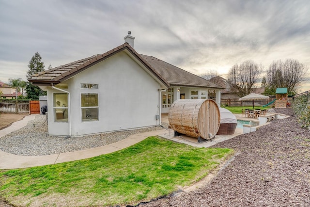 back of house featuring a patio, fence, a tiled roof, and stucco siding