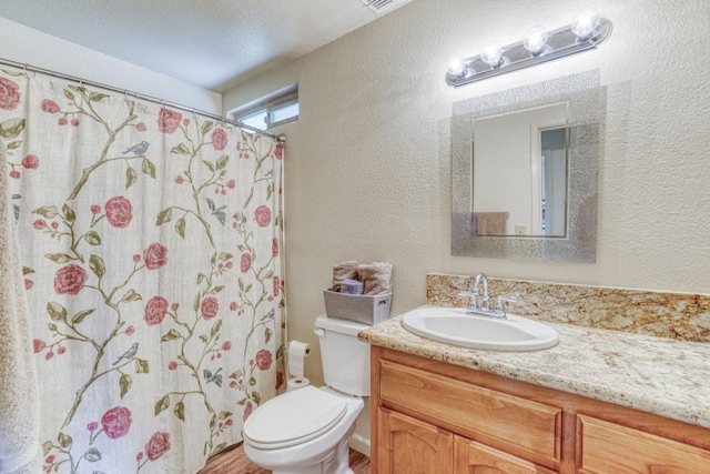 bathroom featuring a textured ceiling, a textured wall, toilet, a shower with shower curtain, and vanity