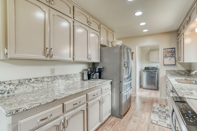 kitchen with recessed lighting, stove, a sink, light wood-style floors, and washer / dryer