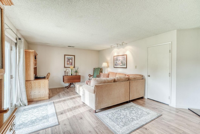 living area featuring visible vents, a textured ceiling, and wood finished floors