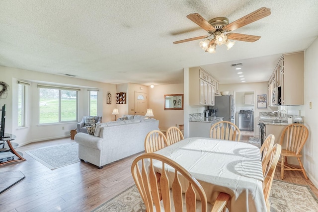 dining space with light wood-style flooring, visible vents, and baseboards