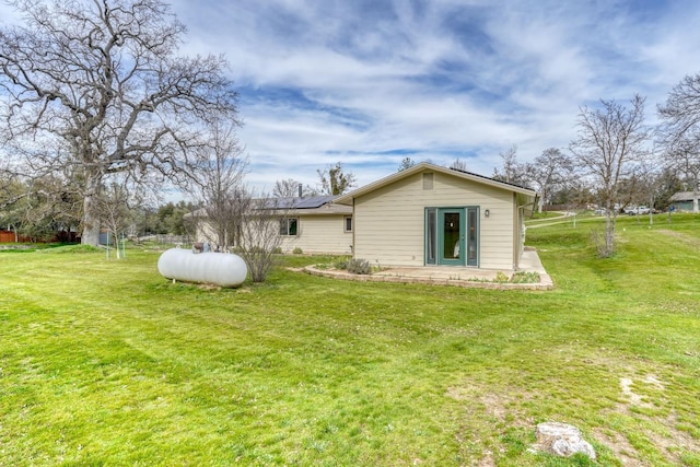 rear view of house with a yard and solar panels