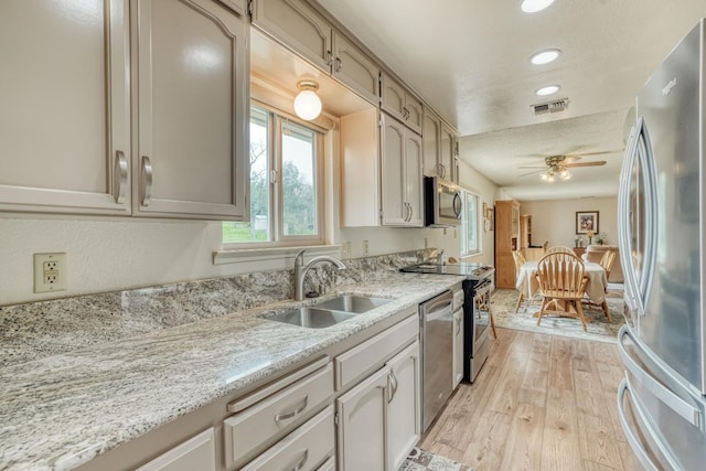 kitchen featuring visible vents, ceiling fan, stainless steel appliances, light wood-type flooring, and a sink