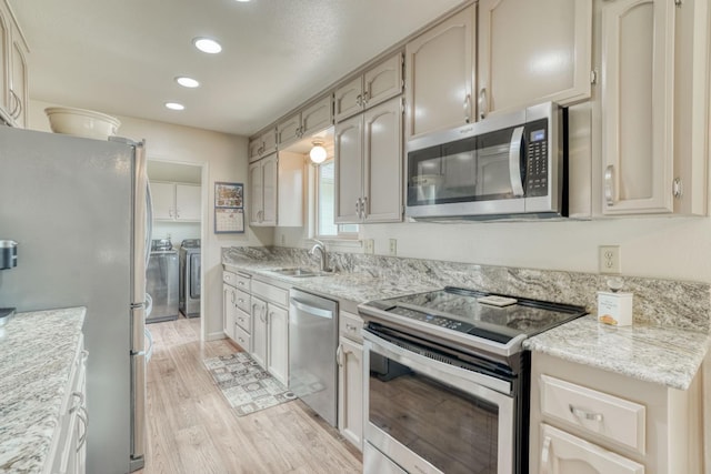 kitchen with recessed lighting, stainless steel appliances, a sink, light wood-style floors, and independent washer and dryer