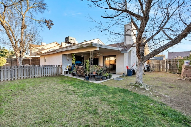 rear view of property with a lawn, ceiling fan, a fenced backyard, a patio area, and stucco siding