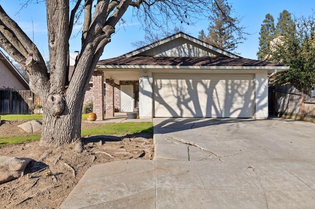 view of front of house featuring a garage, brick siding, and fence