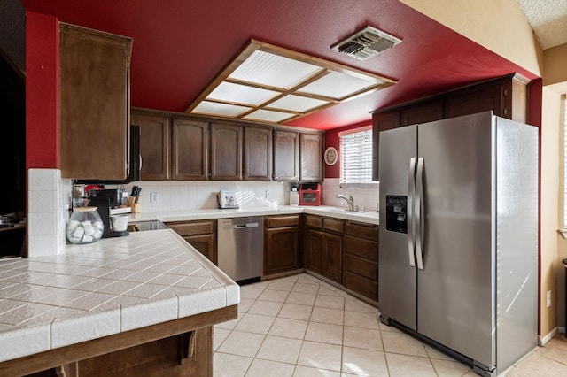 kitchen with light tile patterned flooring, visible vents, appliances with stainless steel finishes, tile counters, and decorative backsplash