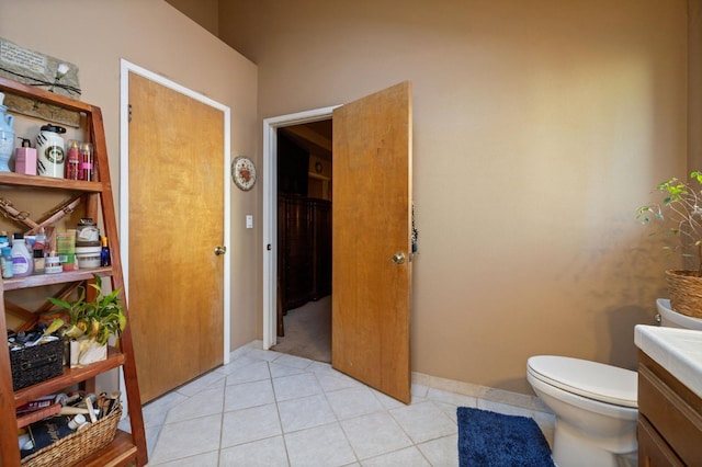 bathroom with toilet, tile patterned flooring, baseboards, and vanity