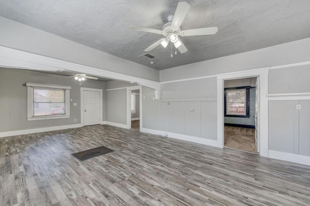 unfurnished living room featuring baseboards, a textured ceiling, a ceiling fan, and wood finished floors