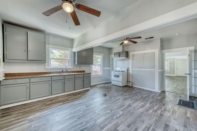 kitchen featuring white gas stove, a sink, visible vents, light wood-type flooring, and gray cabinets