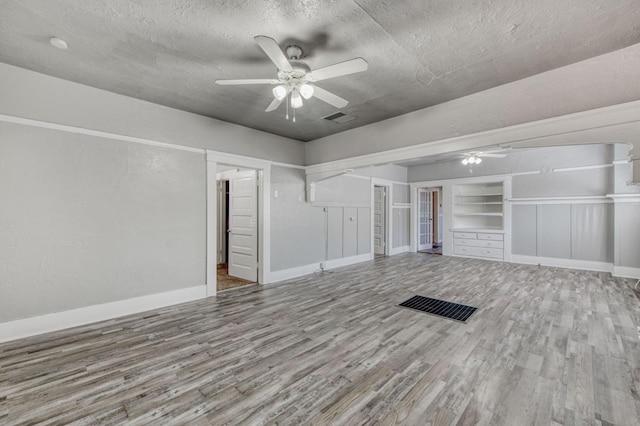 interior space with visible vents, ceiling fan, a textured ceiling, and wood finished floors