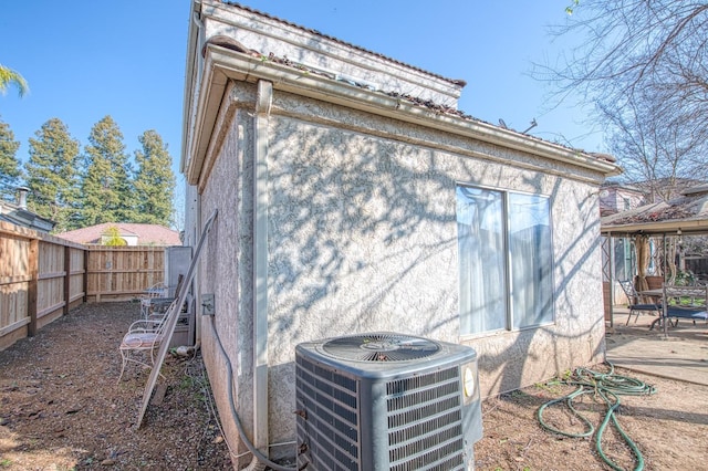 back of property featuring a patio, central AC unit, a fenced backyard, and stucco siding